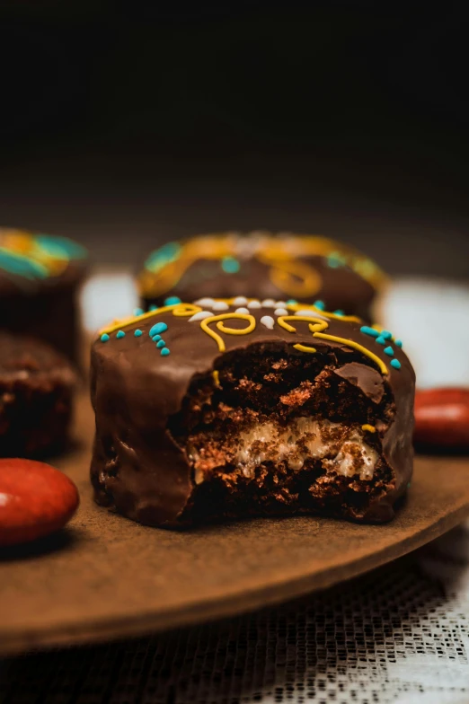 chocolate covered candy sitting on top of a wooden plate, by Dietmar Damerau, unsplash, teal and orange, side view intricate details, donut, high quality photo