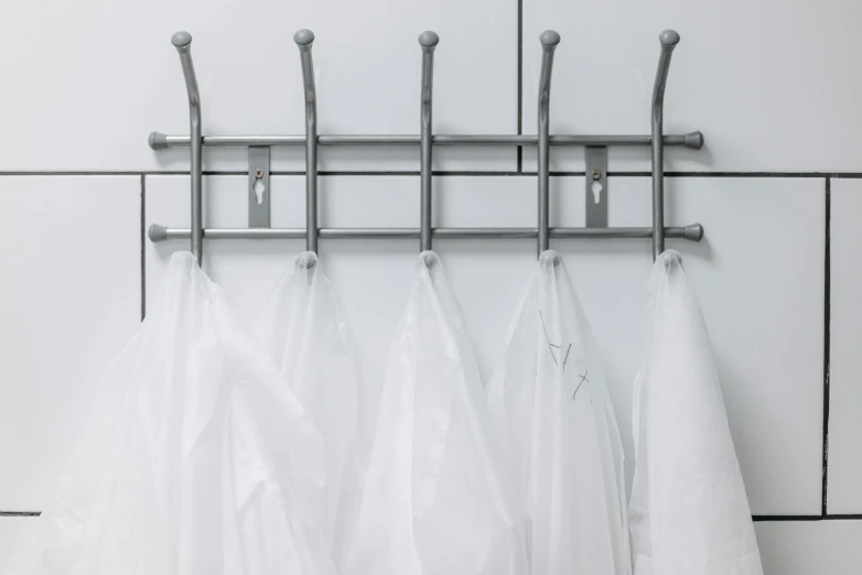 three white aprons hanging on a metal rack, inspired by Bela Čikoš Sesija, bauhaus, artificial spider web, lockers, transparent gray skirts, easy to use