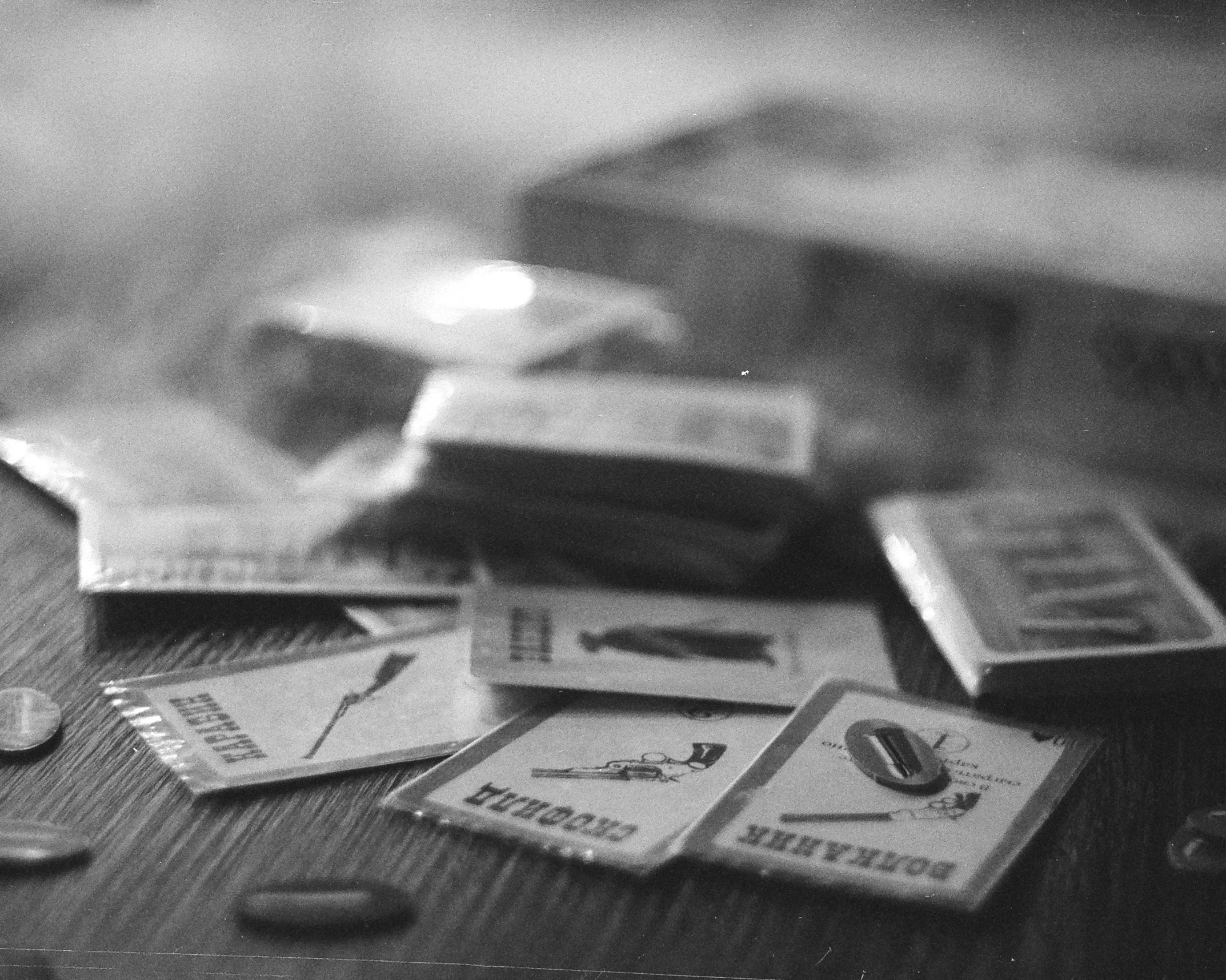 a pile of cigarettes sitting on top of a wooden table, a black and white photo, by Daniel Lieske, playing board games, letterboxing, grainy movie still, taken at golden hour