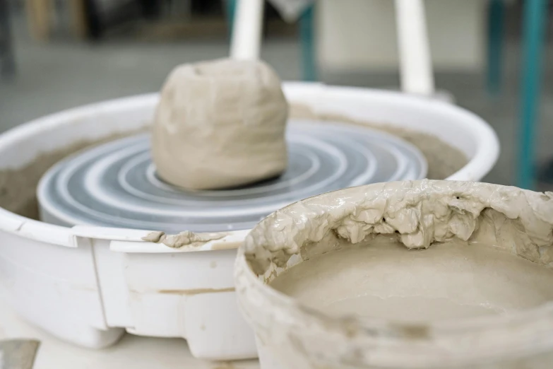 a couple of bowls sitting on top of a table, inspired by Sarah Lucas, unsplash, process art, pulled into the spiral vortex, clay animation, foreground, made in tones of white and grey