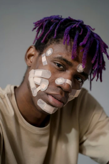 a man with purple hair and white paint on his face, an album cover, trending on pexels, afrofuturism, cute bandaid on nose!!, young man with beautiful face, bandages, stubbles