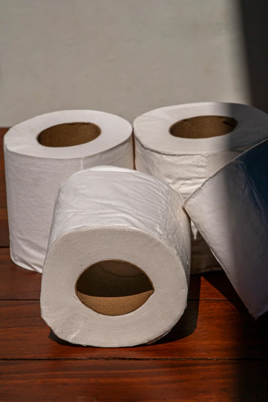 three rolls of toilet paper sitting on top of a wooden table, by Helen Stevenson, square, medium, picture