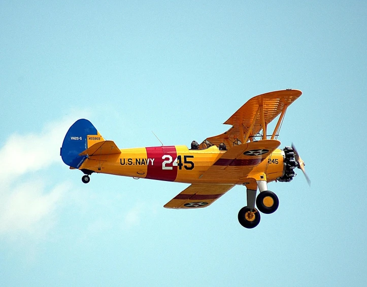 a small yellow airplane flying through a blue sky, a colorized photo, by Dave Melvin, flickr, antique style, nas, replica model, taken in the late 2010s