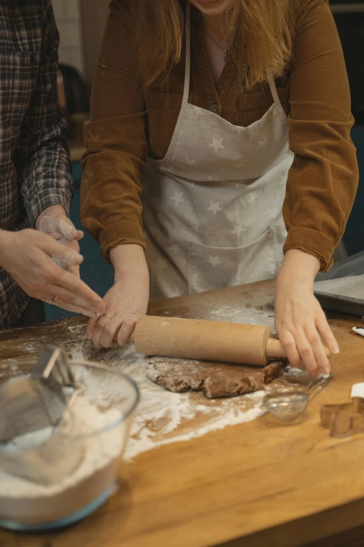 a couple of women standing next to each other in a kitchen, trending on pexels, process art, in the shape of a cinnamon roll, professional woodcarving, thumbnail, hands on counter