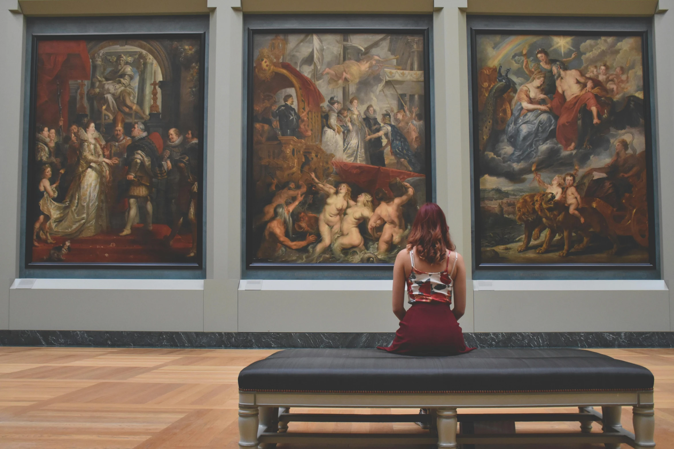 a woman sitting on a bench in front of paintings, inspired by Peter Paul Rubens, pexels contest winner, mannerism, panoramic view of girl, a person standing in front of a, museum quality, facing away