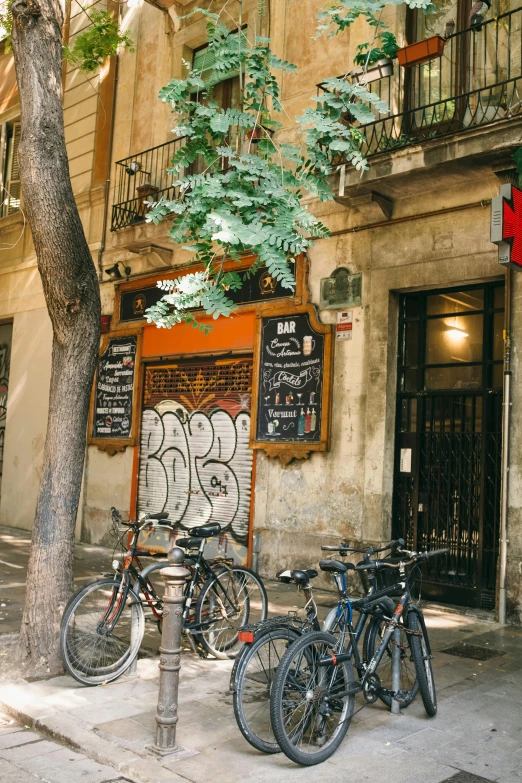 a number of bikes parked in front of a building, by Carlo Carrà, graffiti, local bar, lush surroundings, gothic quarter, exterior view