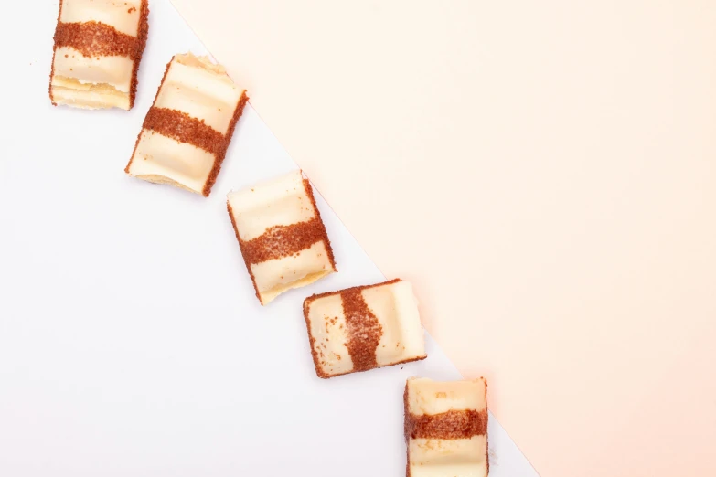 a white plate topped with slices of cake, an album cover, by Emma Andijewska, trending on unsplash, figuration libre, squares, brown and cream color scheme, in a row, 15081959 21121991 01012000 4k