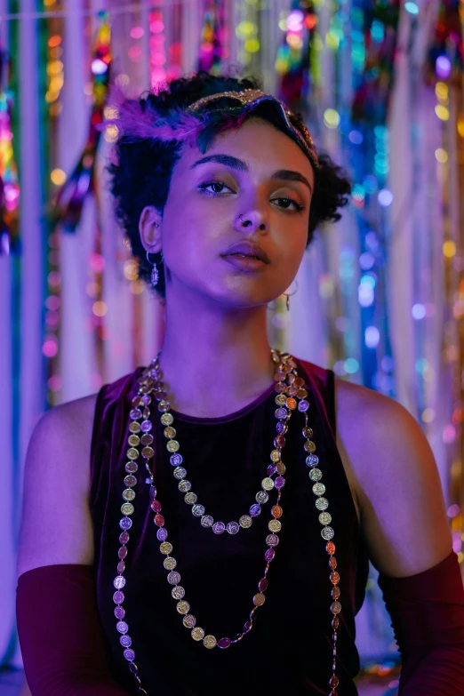 a woman standing in front of a colorful backdrop, jewelry lighting, ashteroth, purple lights, wearing many medallions