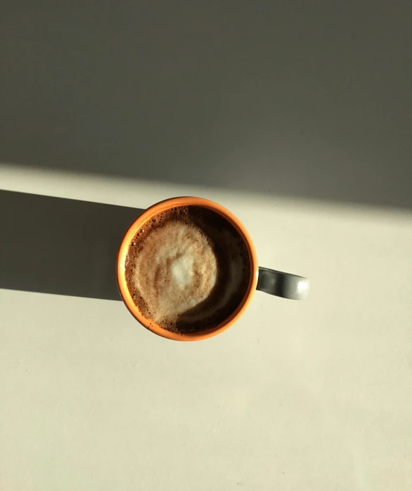 a cup of coffee sitting on top of a table, by Carey Morris, soft shadow, high-quality photo, full daylight, an orange