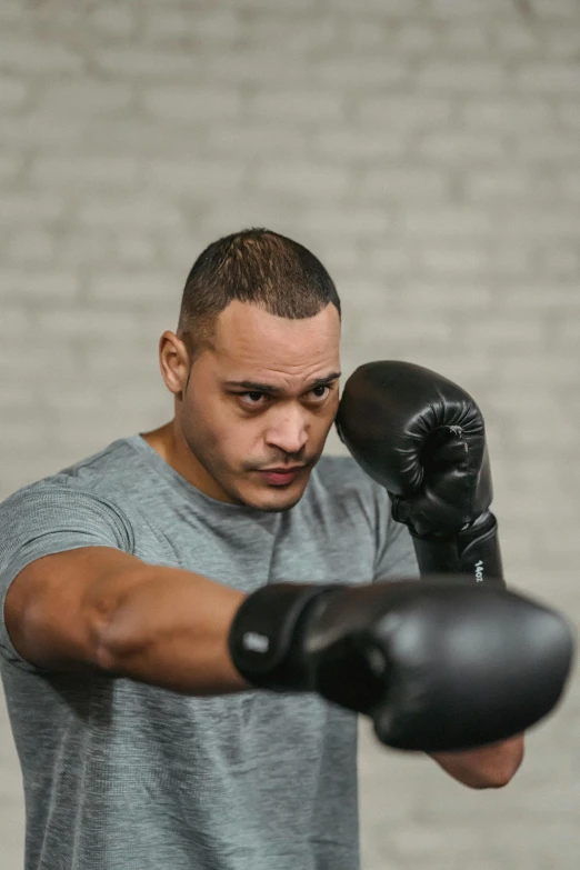 a man in a gray shirt and black boxing gloves, an album cover, inspired by Carlos Berlanga, pexels contest winner, profile image, mixed race, local gym, large forehead