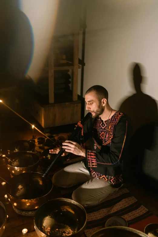 a man sitting on the floor playing a musical instrument, inspired by Aladár Körösfői-Kriesch, light and space, dj at a party, promo image, holy ceremony, standing in a dimly lit room
