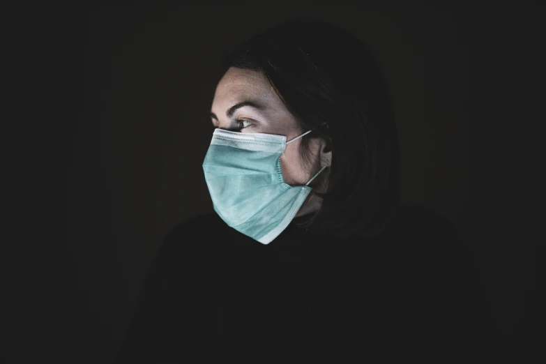 a woman wearing a face mask in the dark, pexels, hyperrealism, healthcare worker, on a gray background, a green, 5 feet away