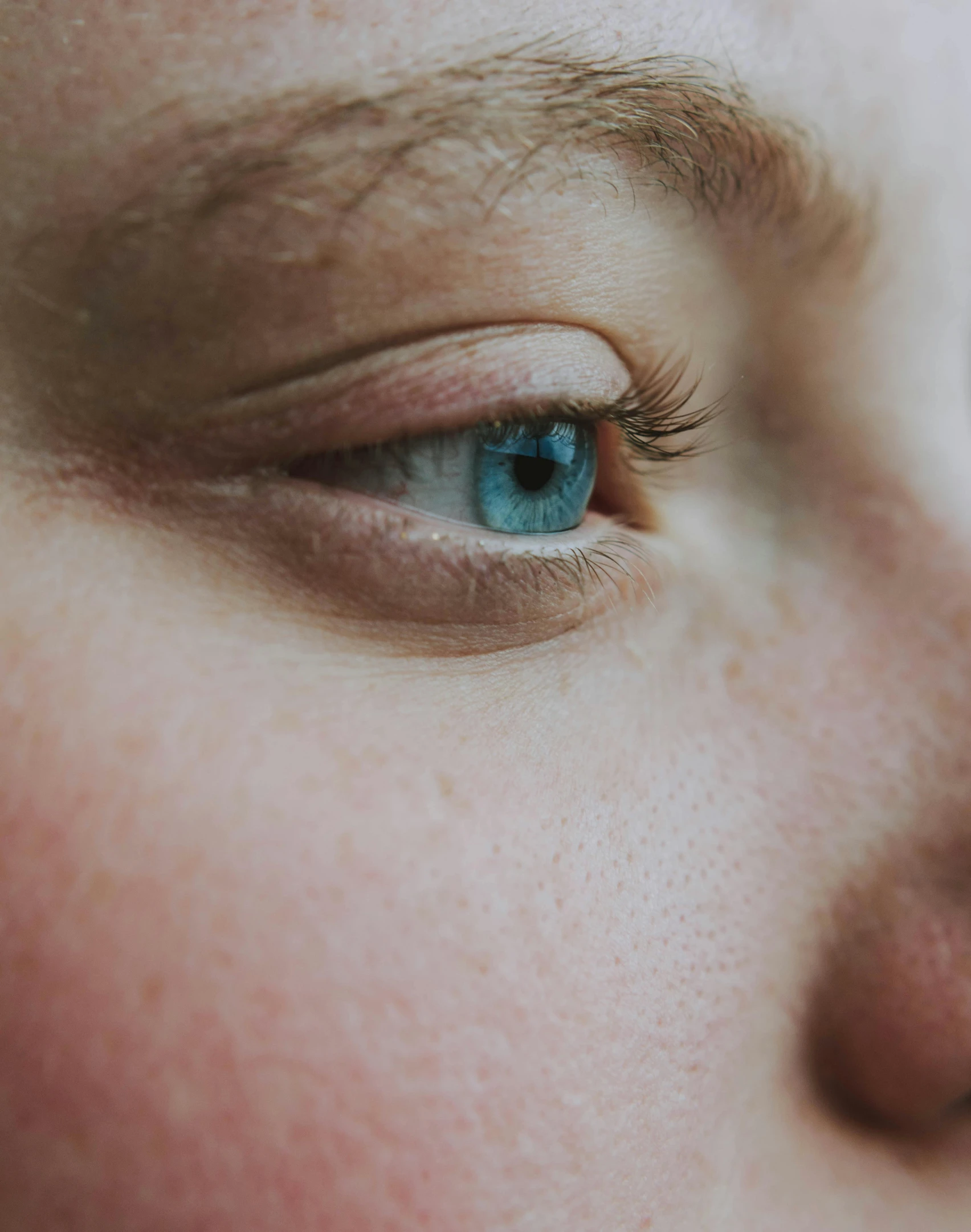 a close up of a person with blue eyes, looking off to the side, queer woman, single eye, face and body clearly visible