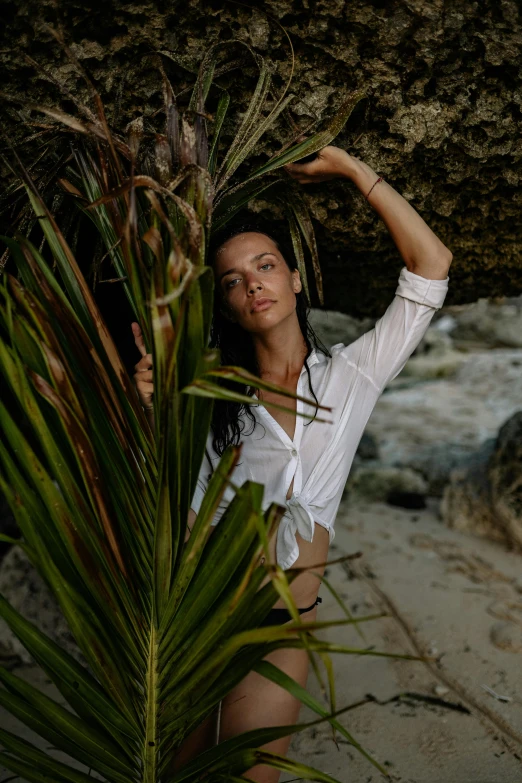 a beautiful woman standing on top of a sandy beach, inspired by Elsa Bleda, unsplash, renaissance, wearing a white button up shirt, in a jungle environment, natural cave wall, evangeline lilly