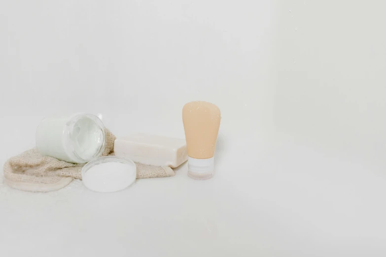 a toothbrush sitting on top of a table next to a jar of toothpaste, by Emma Andijewska, plasticien, beige, miscellaneous objects, white powder makeup, minimalistic background