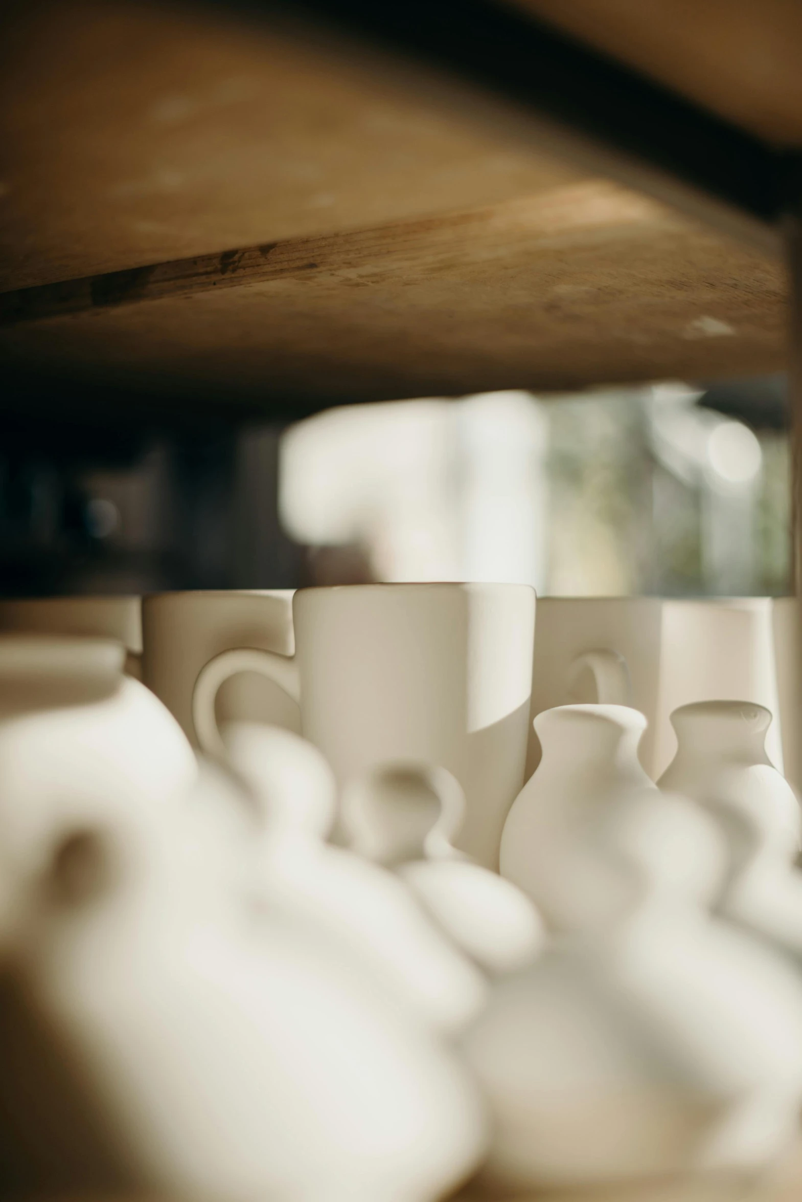 a bunch of cups sitting on top of a shelf, by Hendrik Gerritsz Pot, trending on unsplash, natural soft light, off-white plated armor, in a workshop, bottom body close up