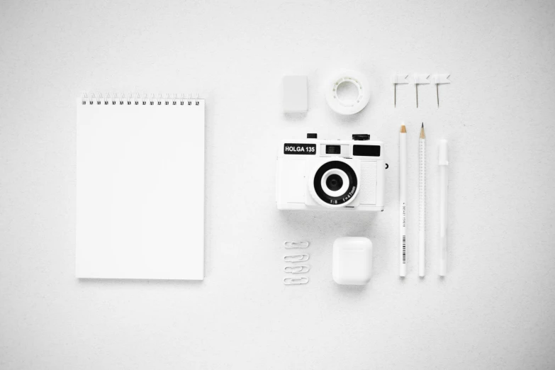 a camera, pencils, erases, and a notepad on a white surface, a black and white photo, by Andrei Kolkoutine, unsplash contest winner, minimalism, all white, white clothing, vector graphic, digital art #oneshotgame