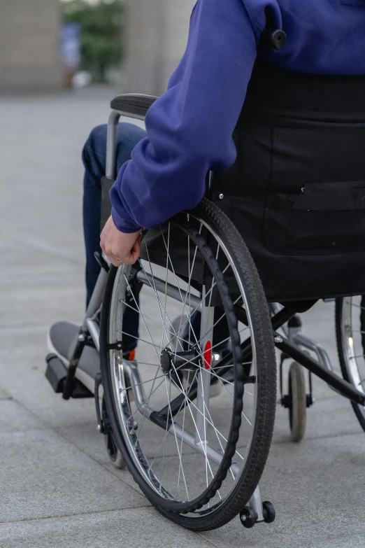 a person in a wheel chair on a sidewalk, pexels, hurufiyya, on a gray background, digital image, caparisons, closeup of arms