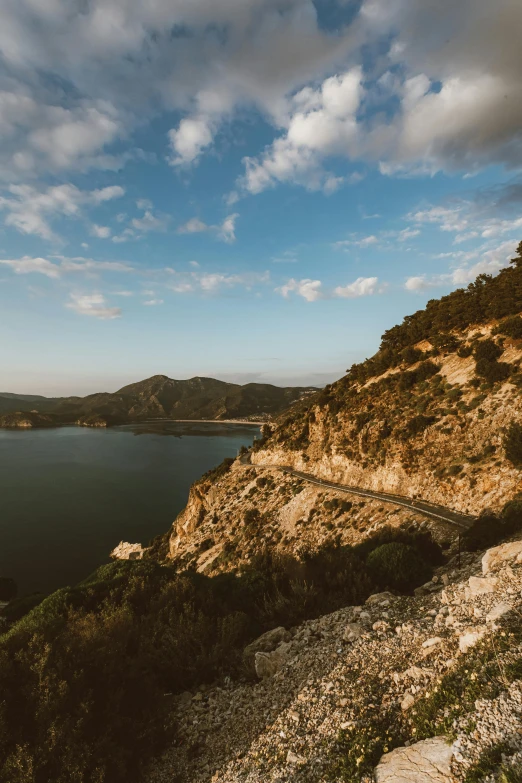 a man standing on top of a mountain next to a body of water, marbella landscape, road between hills, 8k 28mm cinematic photo, multiple stories