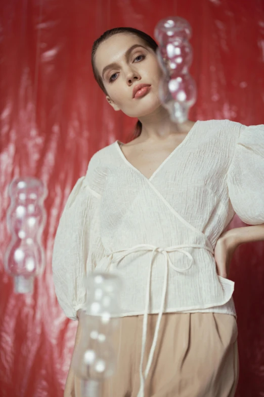 a woman standing in front of a red background, inspired by Elsa Bleda, renaissance, wearing white v - neck top, puff sleeves, off - white collection, manila