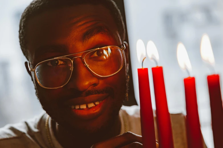 a close up of a person holding a bunch of candles, an album cover, pexels contest winner, wearing red tainted glasses, david uzochukwu, smiling slightly, bisexual lighting