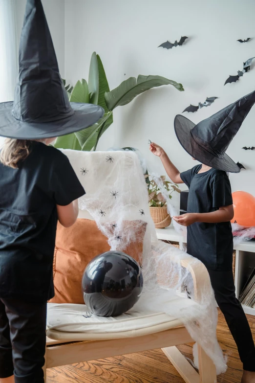 two children dressed up as witches in a living room, process art, black pointed hat, ignant, foam, trick or treat