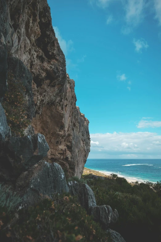 a person standing on top of a cliff next to the ocean, rock climbing, australian beach, slightly pixelated, trending photo