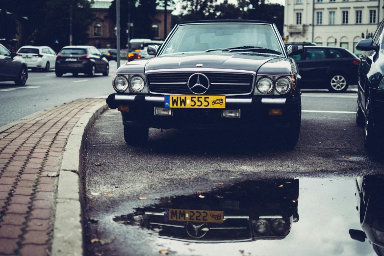 a car parked on the side of a road next to a puddle of water, by Sebastian Spreng, pexels contest winner, looking regal and classic, mercedez benz, 80s nostalgia, helsinki