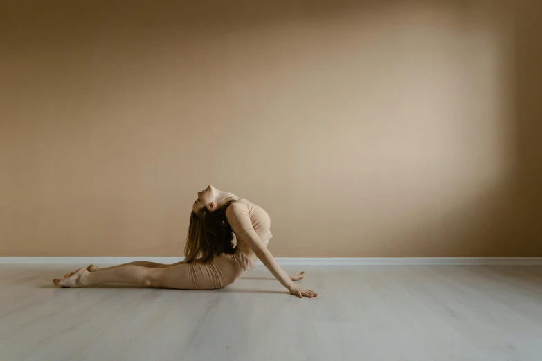 a woman is doing a yoga pose on the floor, by Emma Andijewska, pexels contest winner, arabesque, smooth gold skin, beautiful girl in an empty room, lane brown, forward facing pose