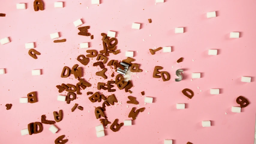a pink background with chocolate letters and marshmallows, by Julia Pishtar, debris spread, detail shot, large eddies, product shot