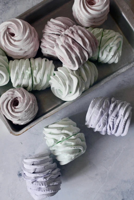 a tray of cupcakes sitting on top of a table, a colorized photo, inspired by Perle Fine, trending on unsplash, spiral smoke, loose white braid, bottom body close up, marshmallow