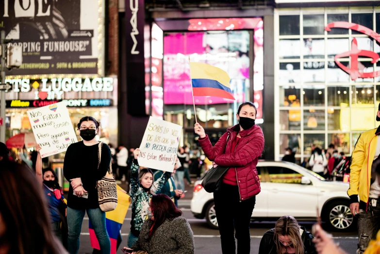 a group of people holding signs on a city street, a photo, by Gina Pellón, pexels, pink yellow and blue neon signs, flag in hands, [ theatrical ], square