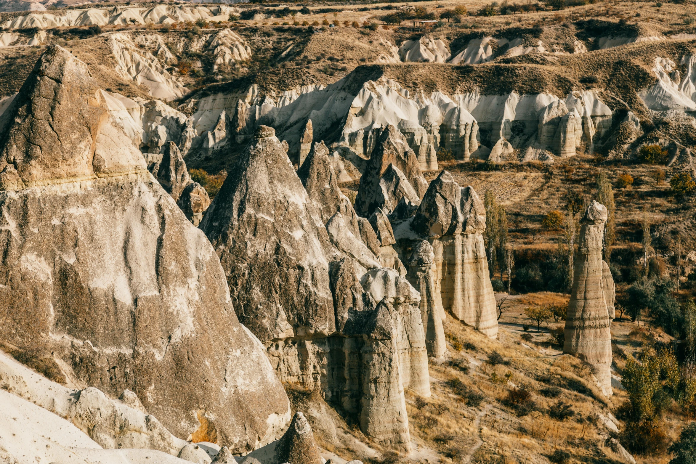 a group of people standing on top of a mountain, by Emma Andijewska, pexels contest winner, art nouveau, chiseled formations, beige, white, bells