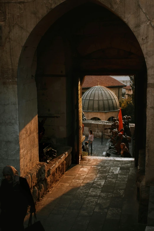 an archway leading to a building with a dome in the background, sun down, looking down from above, damascus, shady alleys