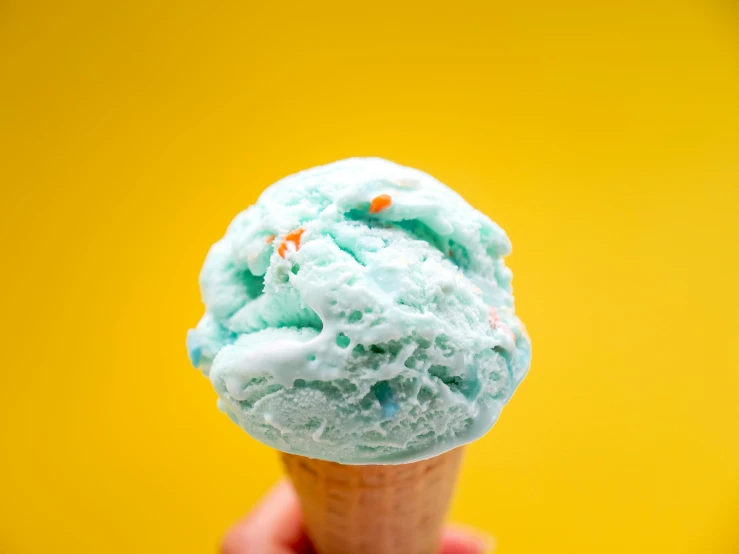 a close up of a person holding an ice cream cone, a pastel, trending on pexels, blue-green fish skin, dayglo blue, 1940s food photography, yellow and blue