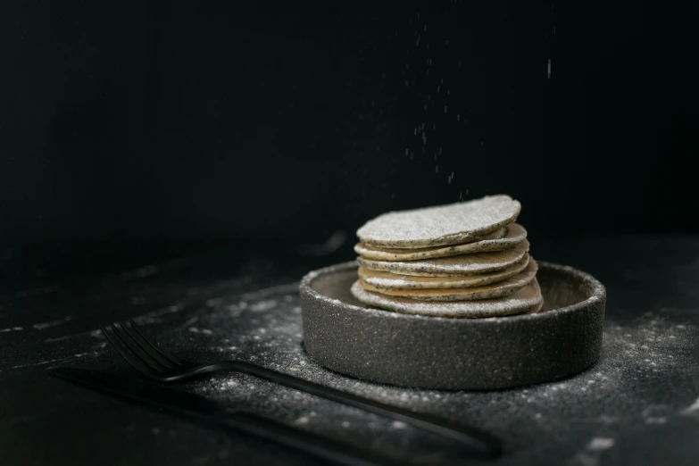 a stack of pancakes sitting on top of a plate, unsplash, sugar snow, dark and dusty, silver white and gold, miniature product photo