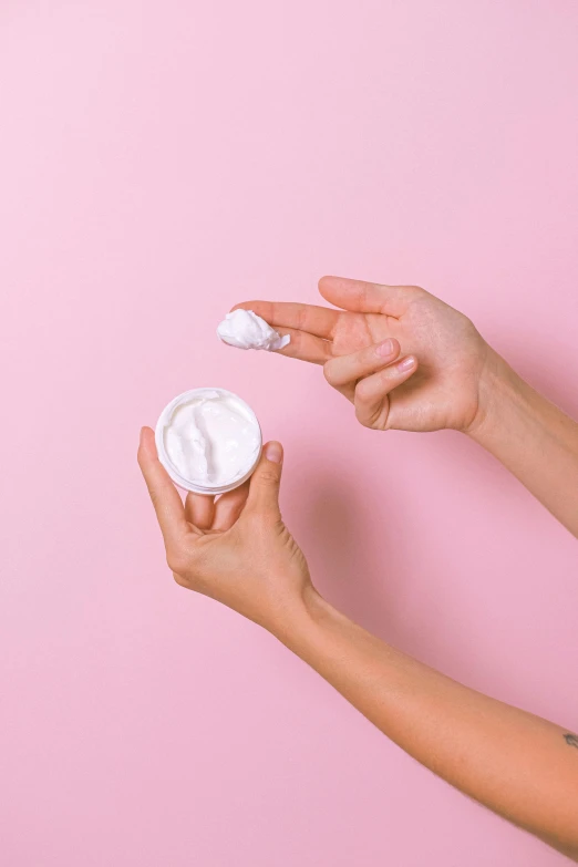 a woman holding a jar of cream on a pink background, a picture, by Nicolette Macnamara, trending on pexels, made of lab tissue, product view, viewed from behind, how-to