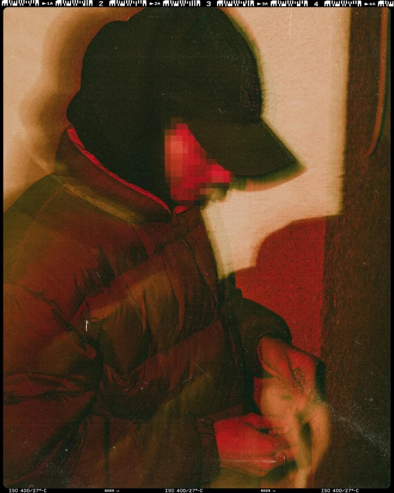 a close up of a person wearing a hat, an album cover, by Attila Meszlenyi, neo-figurative, red light from some windows, model wears a puffer jacket, heavy jpeg artifact blurry, pixellated