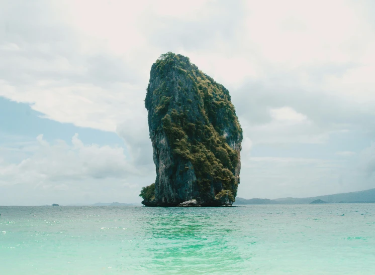 a large rock in the middle of a body of water, pexels contest winner, tropical island, tall thin, ornately detailed, limestone