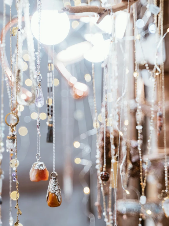 a bunch of necklaces hanging from a tree branch, trending on pexels, light and space, shop window for magical weapons, crystal lights, beaded curtains, silver gold red details