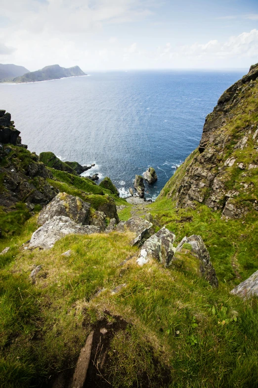 a large body of water sitting on top of a lush green hillside, inspired by Johan Christian Dahl, rocky coast, narrow footpath, devils horns, steps