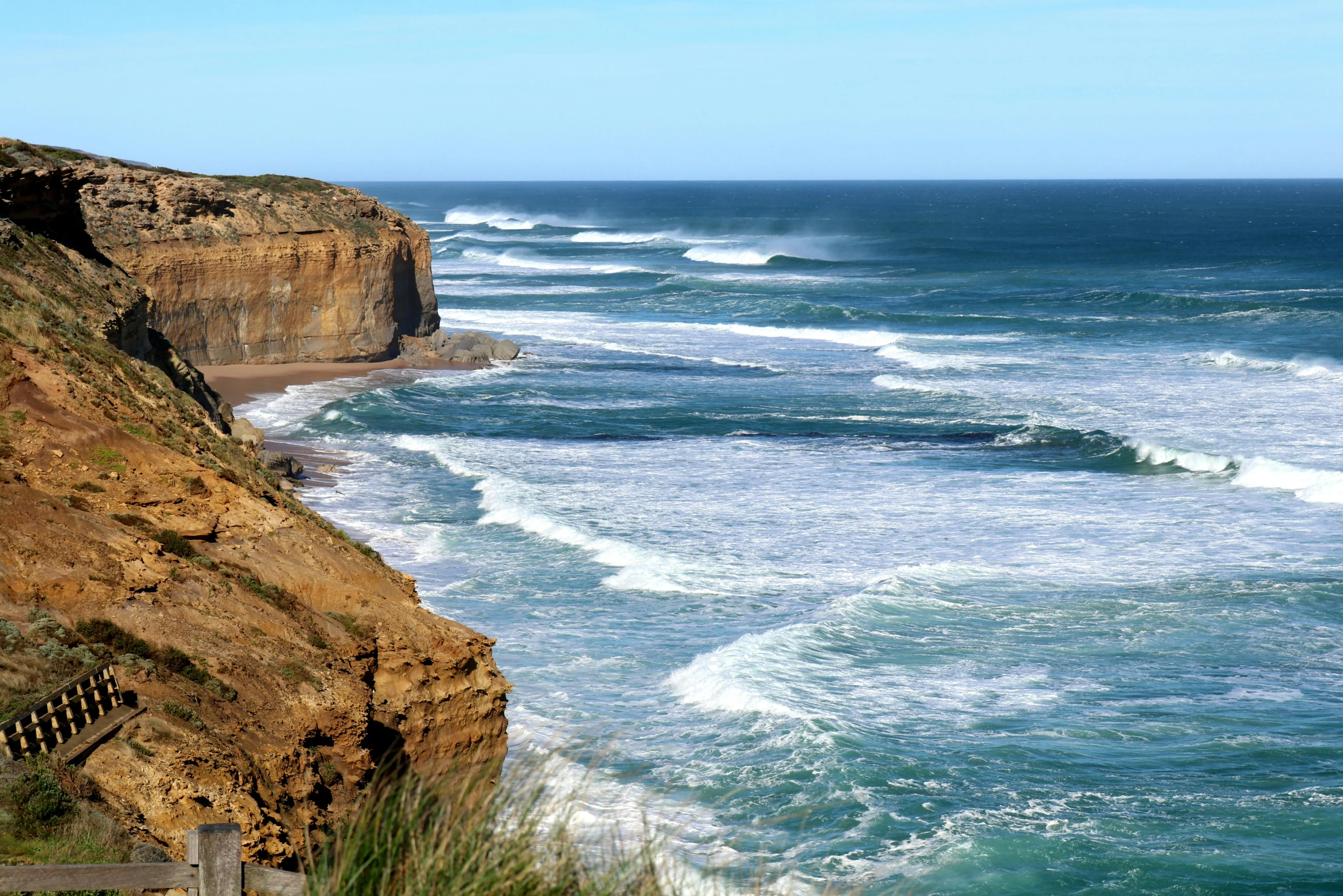 a bench sitting on top of a cliff next to the ocean, victorian arcs of sand, surfing, songlines, standing on a cliffside