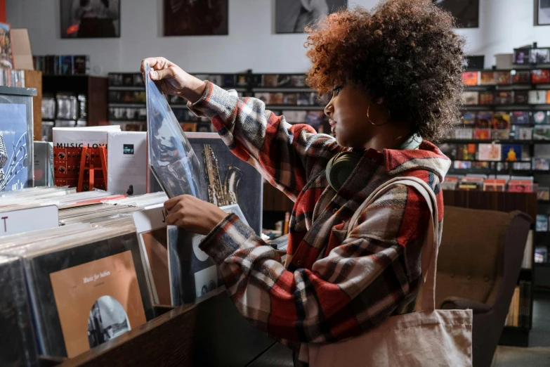 a woman looking at cds in a record store, an album cover, by Everett Warner, pexels contest winner, black arts movement, imaan hammam, artist wearing overalls, fine art print, high quality print