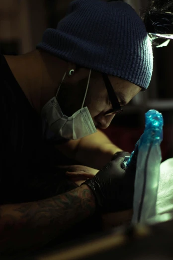 a man getting a tattoo on his arm, by Adam Marczyński, cold blue light, ice - carving, slide show, documentary
