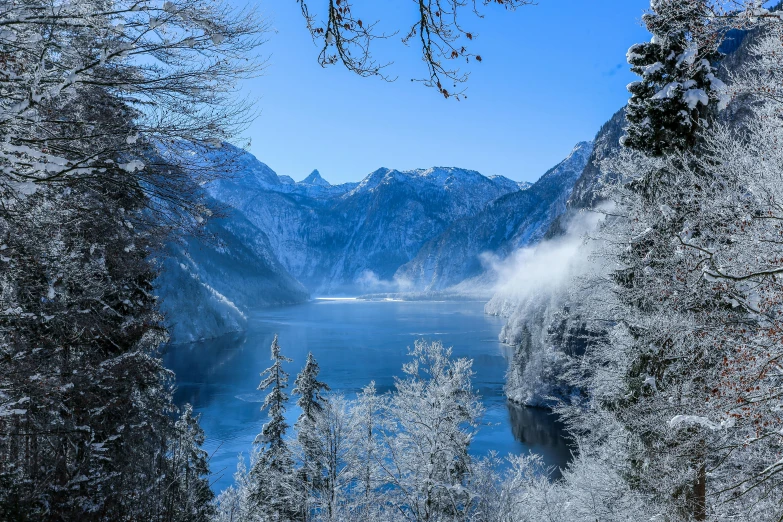 a large body of water surrounded by snow covered trees, by Sebastian Spreng, pexels contest winner, blue glacier, slide show, thumbnail, germany