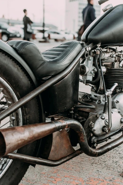 a close up of a motorcycle parked on a street, by Tom Bonson, pexels contest winner, auto-destructive art, exposed metal bones, leather, restomod, black