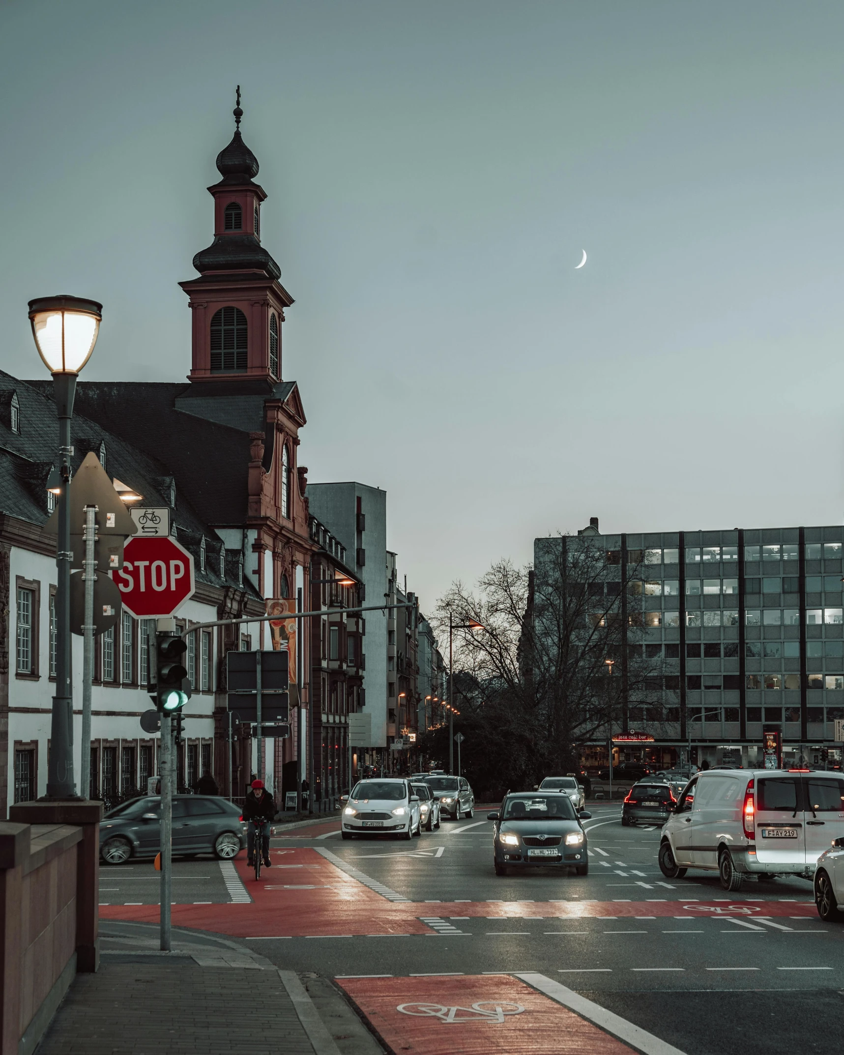 a red stop sign sitting on the side of a road, by Kristian Zahrtmann, pexels contest winner, berlin secession, city street at dusk, detmold, big moon on the right, standing in a city center