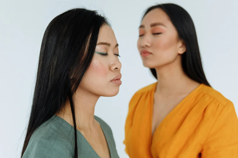 a couple of women standing next to each other, inspired by Wang Duo, trending on pexels, realism, closed eyes, skincare, asian human, coloured