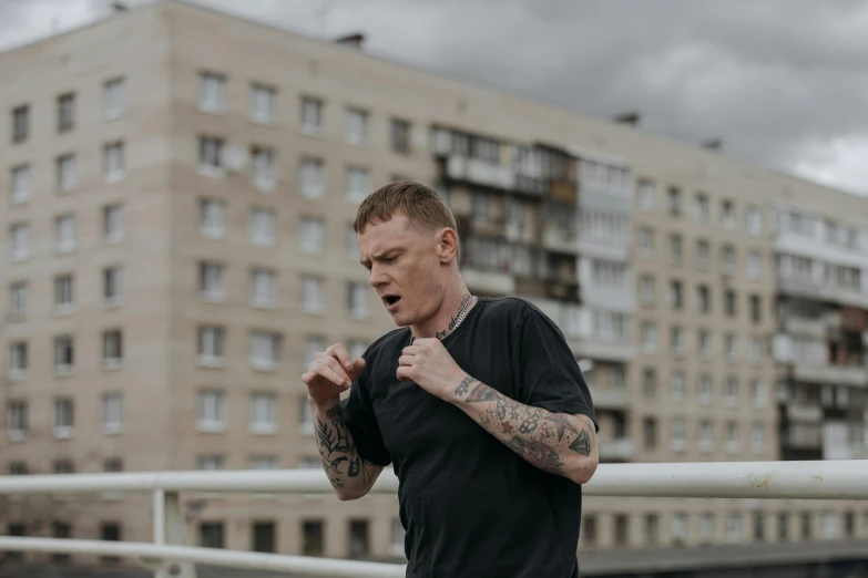 a man with tattoos standing in front of a building, by Emma Andijewska, pexels contest winner, in a boxing ring, vitalik buterin, promotional image, lachlan bailey