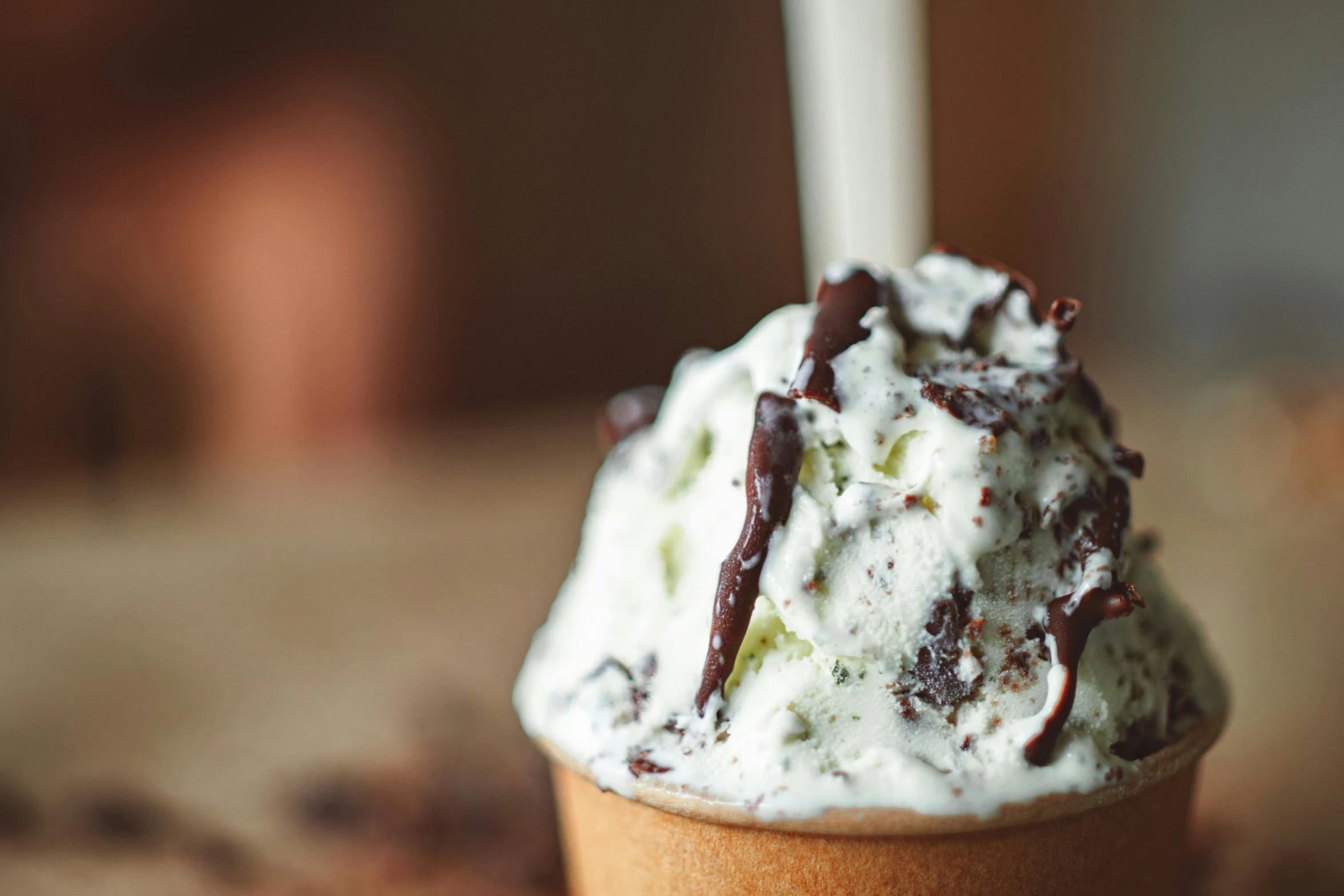 a cup of ice cream sitting on top of a table, dark brown white green colours, up close, product shot, feature